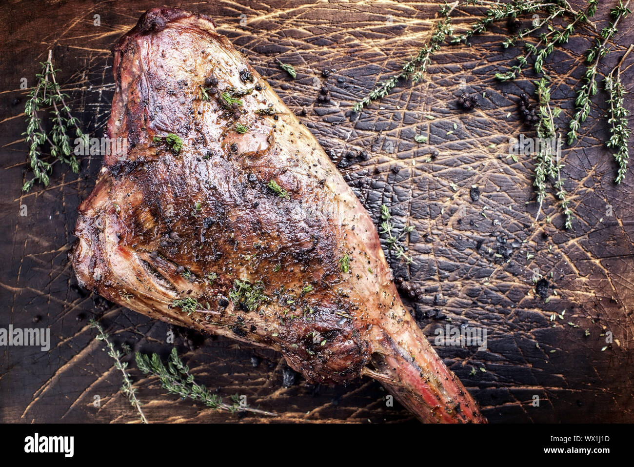 Marinata di barbecue gamba invecchiata di cervo con erbe aromatiche come vista dall'alto su una scheda rustico Foto Stock