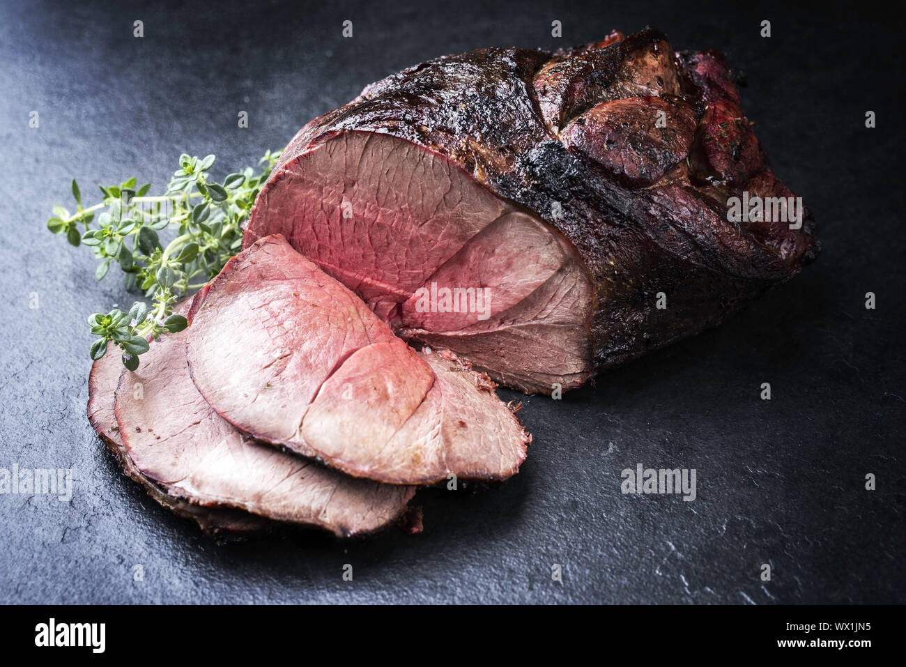 Barbecue secca haunch invecchiato di cervo con erbe aromatiche come close-up su una scheda Foto Stock