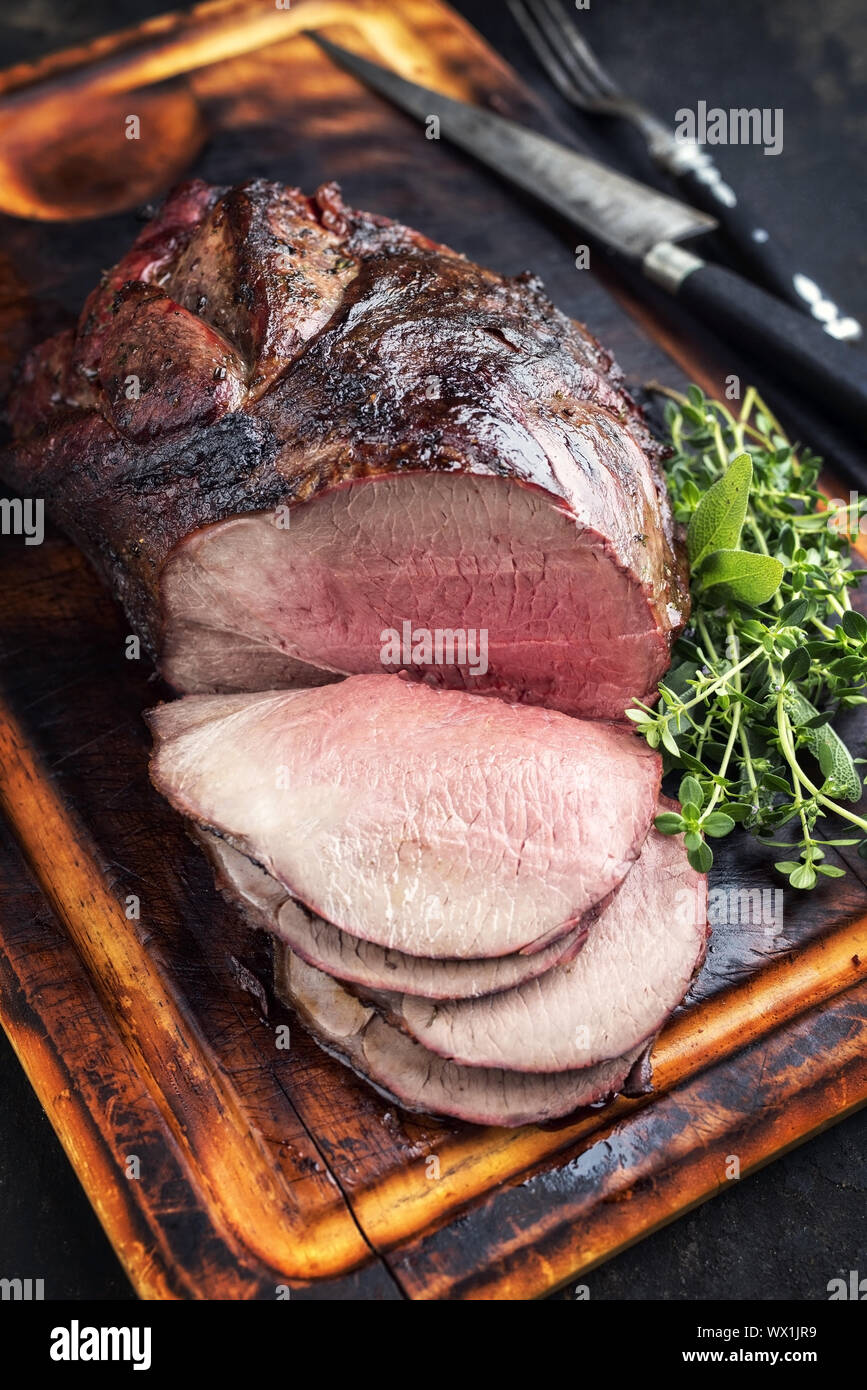 Barbecue secca haunch invecchiato di cervo con erbe aromatiche come close-up su un tagliere Foto Stock