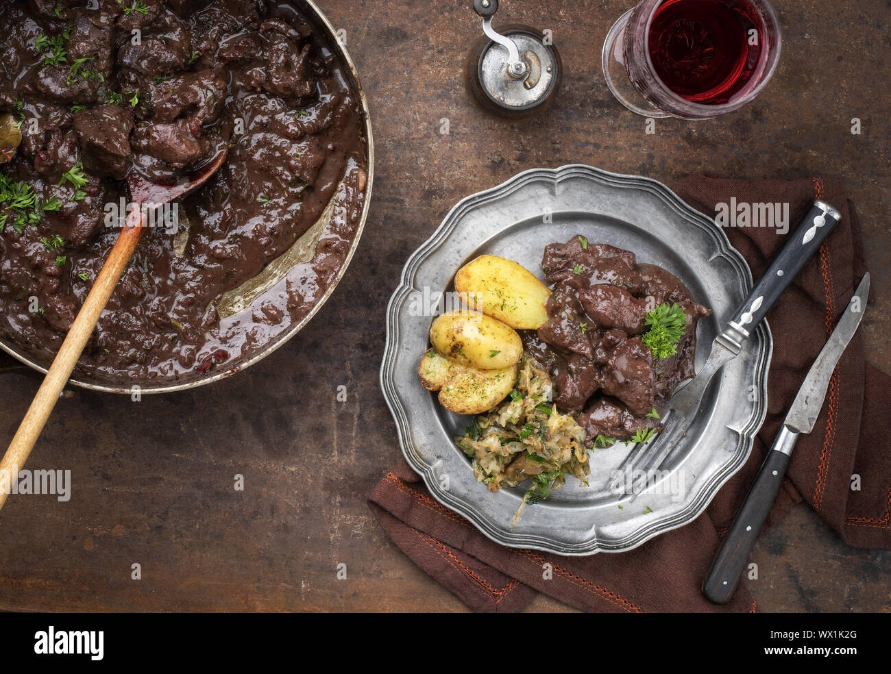 Carni di vitello ragù di fegato in salsa di vino rosso con patate fritte e crauti come vista dall'alto su una piastra Foto Stock