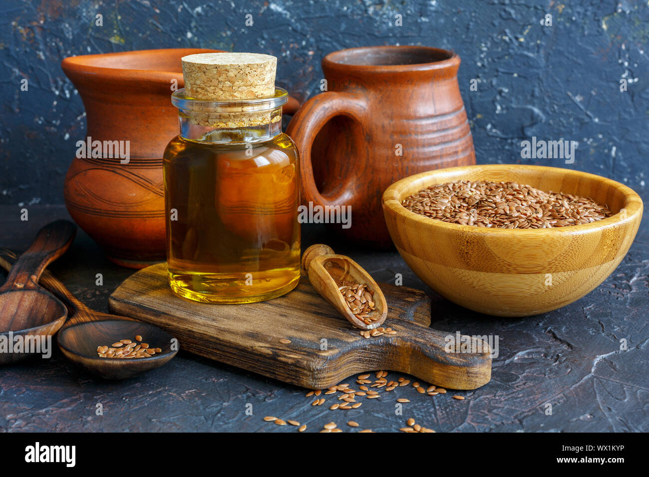 Bottiglia di olio di lino spremuto a freddo e semi di lino in una ciotola di legno. Foto Stock