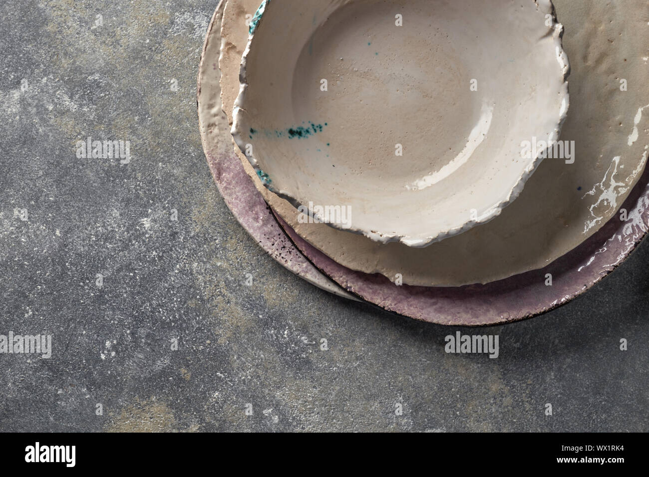 Porcellana vaschette vuote e le piastre sul grigio di una tavola di marmo. Multi-ceramici colorati vintage piatti artigianali. Vista dall'alto. Foto Stock