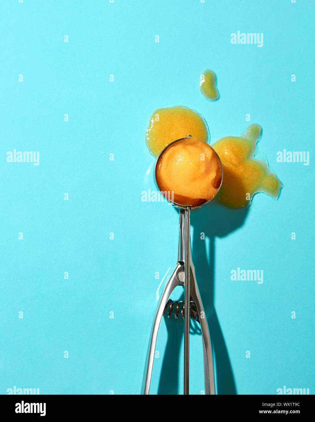 Piatto di laici un cucchiaio per gelato con Giallo mango dessert e fusa gelati su uno sfondo blu con il disco di ombre Foto Stock