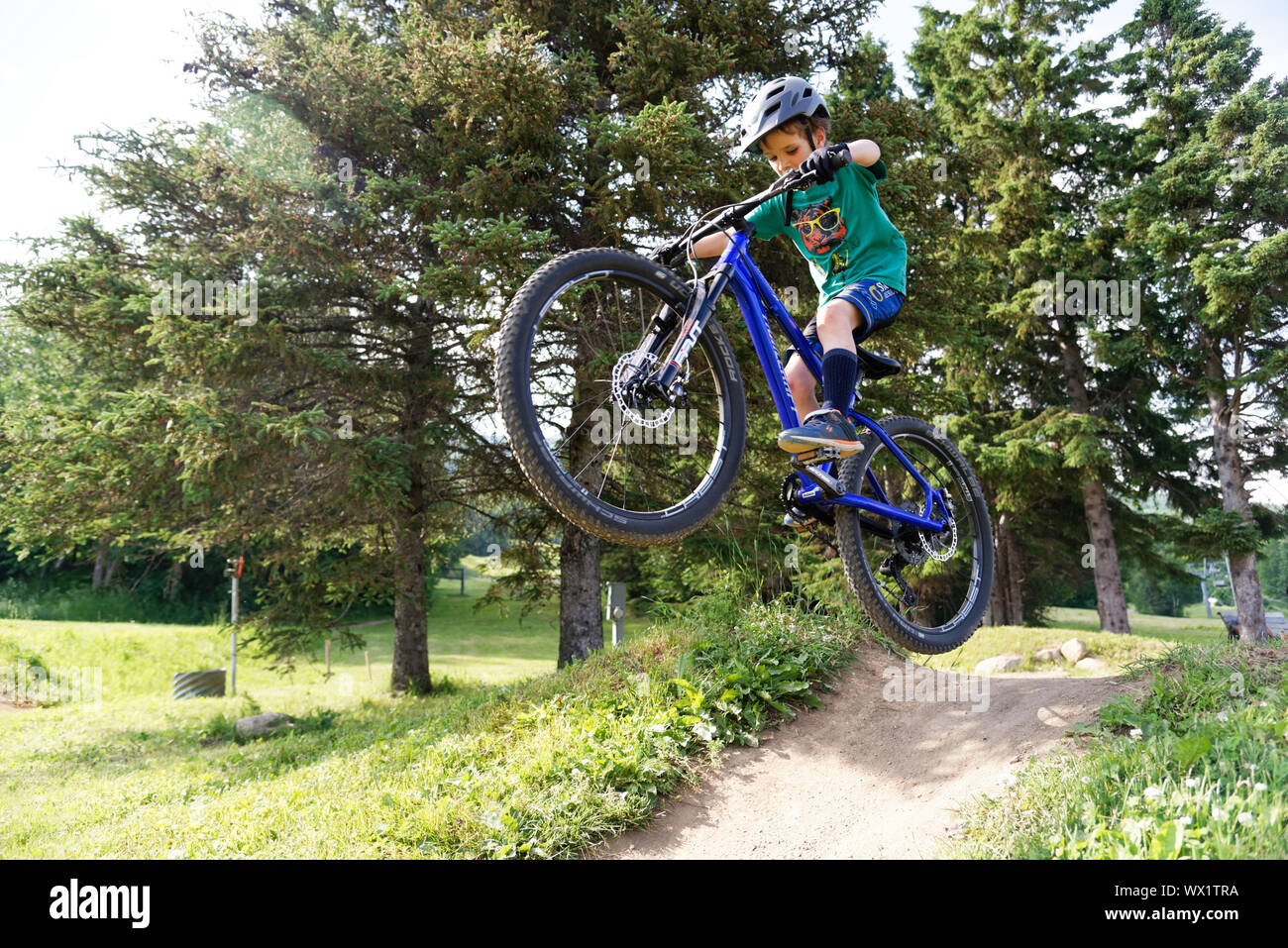 A sette anni di vecchio ragazzo facendo salta sulla sua mountain bike Foto Stock