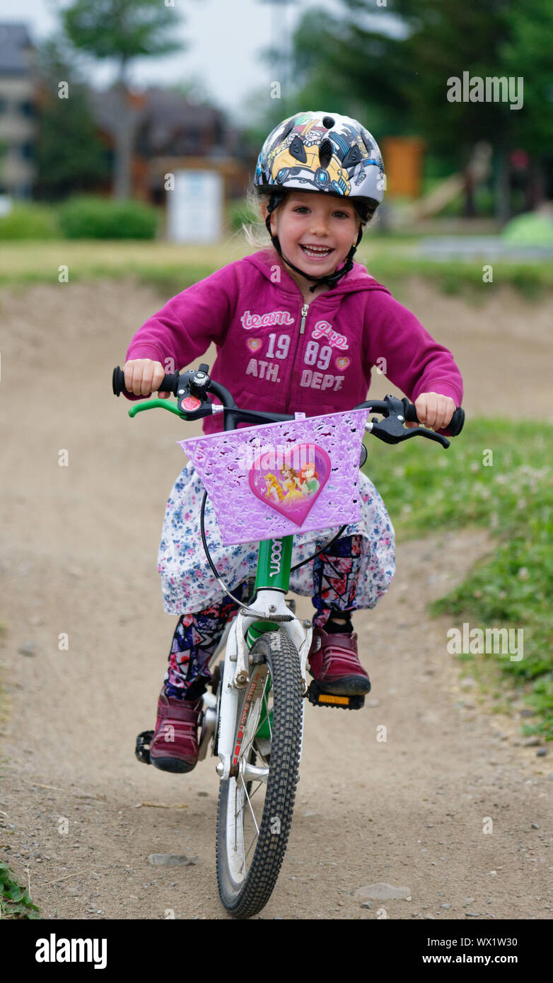 Una bambina di 5 anni) la trasmissione via IR con gioia come le corse la sua bici Foto Stock