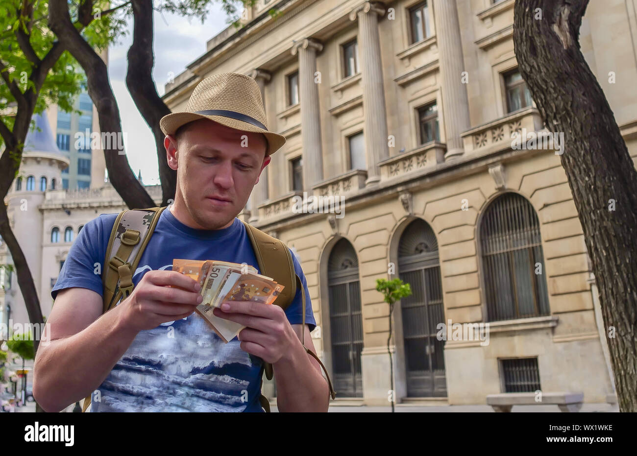 Giovane maschio conteggi turistica contanti sulla strada della città Foto Stock