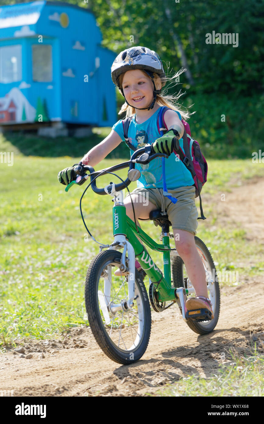 Una bambina di 5 anni) sorridendo come lui corre in suo bike Foto Stock