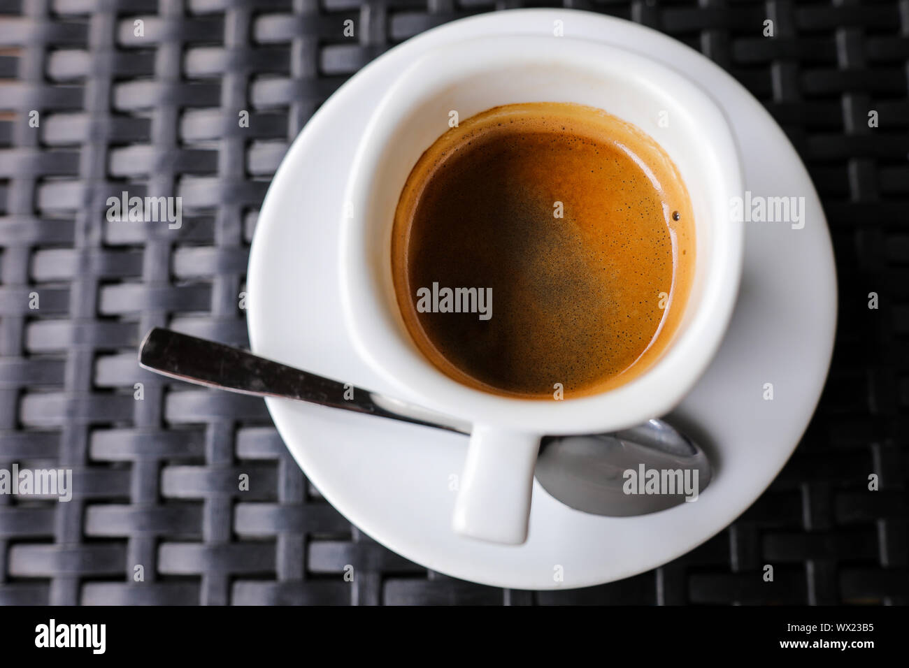 Dettagli con un bianco di ceramica tazza di caffè e un acciaio inossidabile cucchiaio in una tabella in un coffee shop Foto Stock
