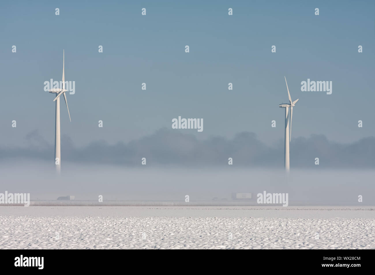 Olandese paesaggio invernale con autostrada, terra della nebbia e delle turbine a vento Foto Stock