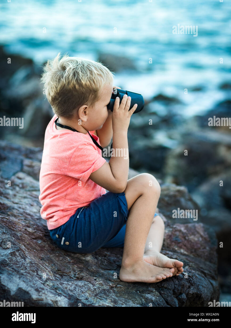 Little Boy guardando lontano con il binocolo Foto Stock