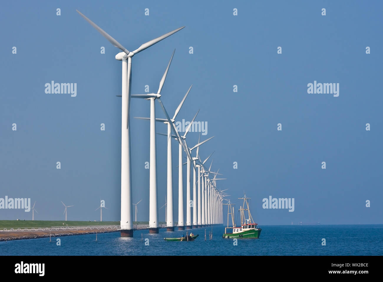 La nave da pesca vicino a una fila af big windturbines nel mare olandese Foto Stock