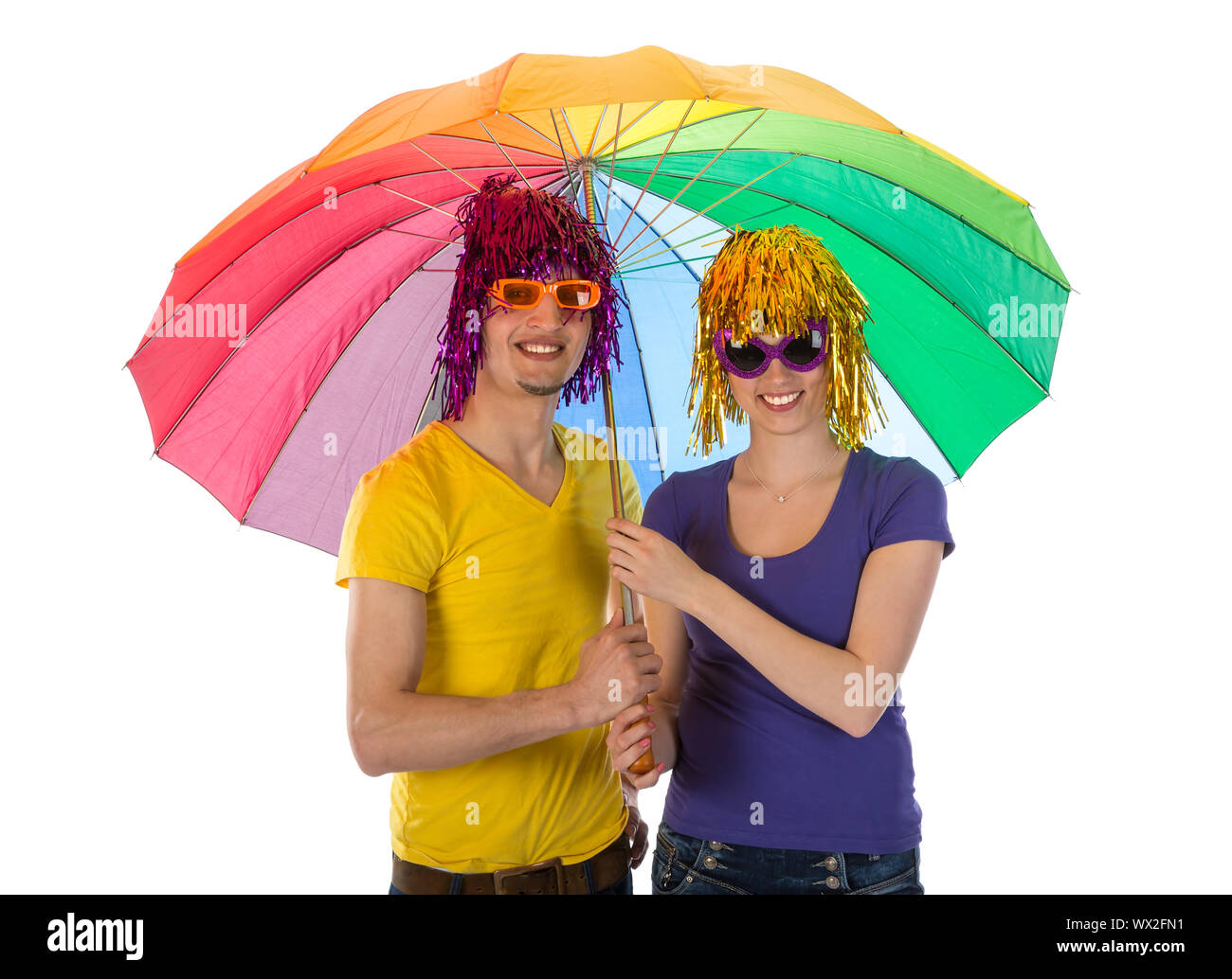 Moda giovane con occhiali da sole e parrucche coperti da un arcobaleno unbrella Foto Stock