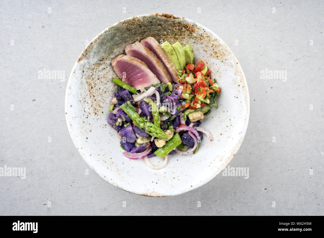 Moderno e fritture di pesce di tonno Sashimi filetto con Insalata di asparagi verdi patate blu und vegetale condimento al Peperoncino come vista dall'alto su una piastra Foto Stock