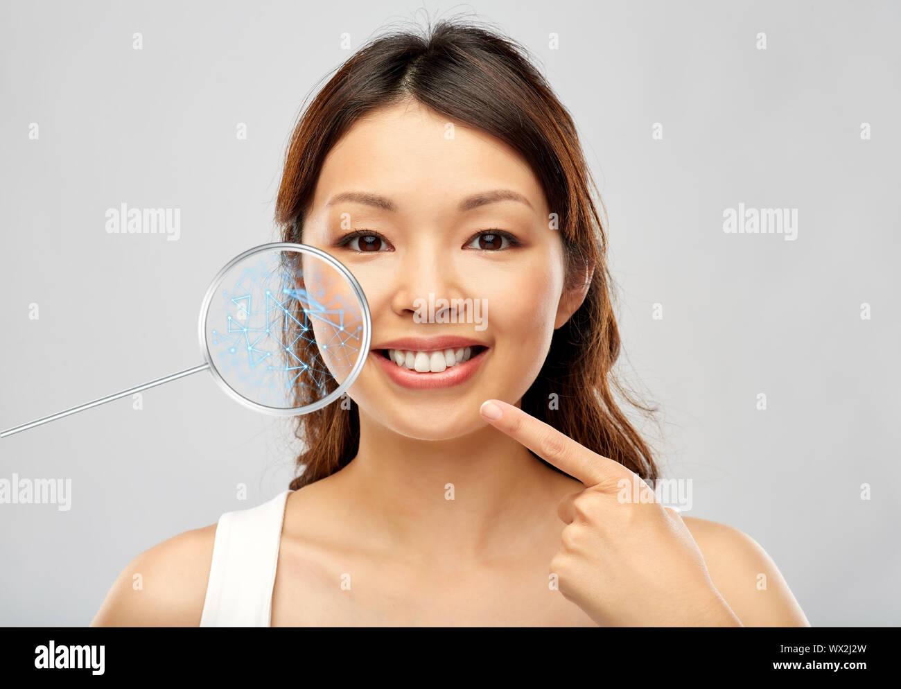 Sorridenti giovane donna asiatica di toccare il suo volto Foto Stock