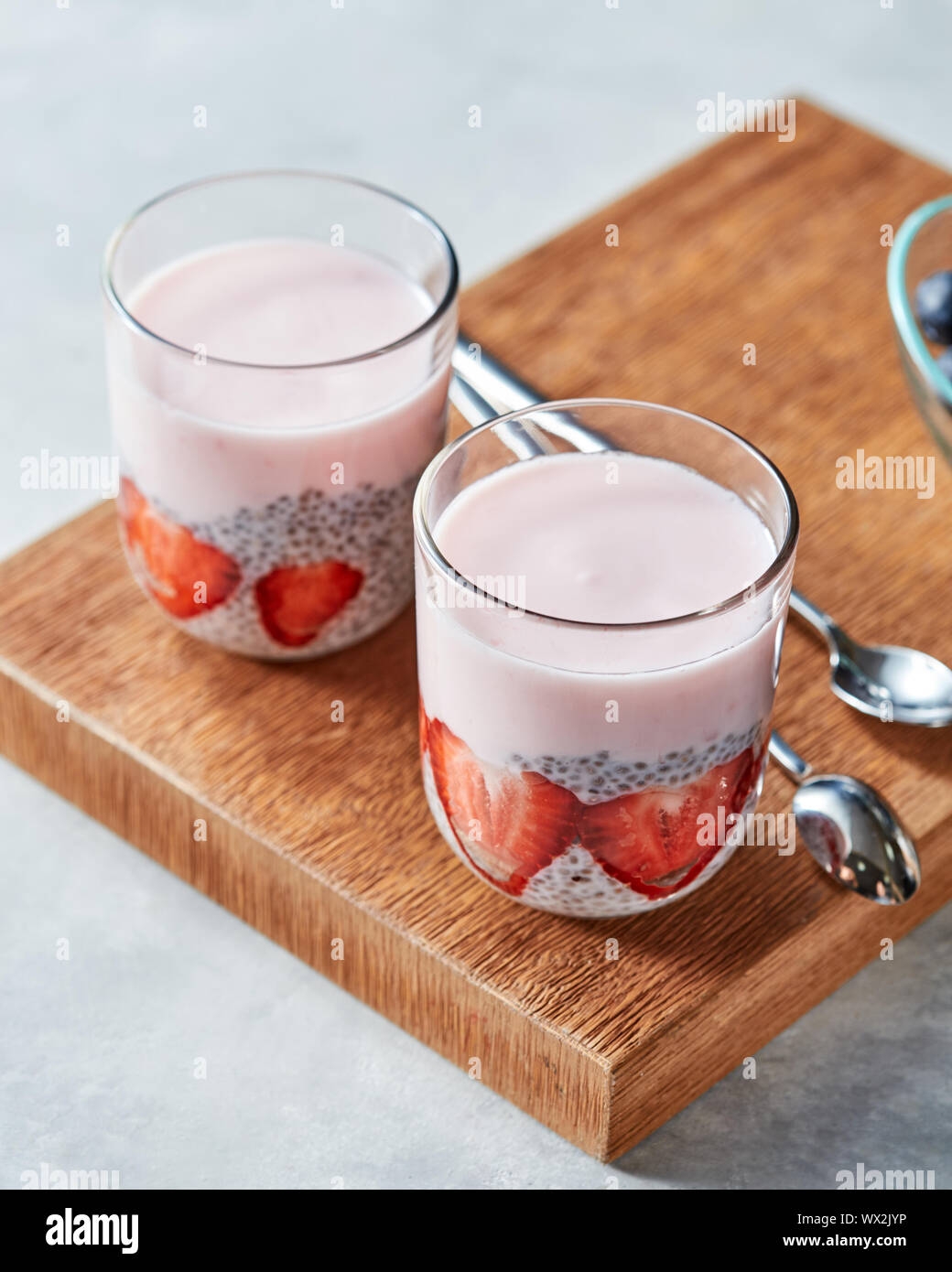 Layered yogurt, dessert fatti in casa con fragole mature, budino di chia in vetro su uno sfondo di legno Foto Stock