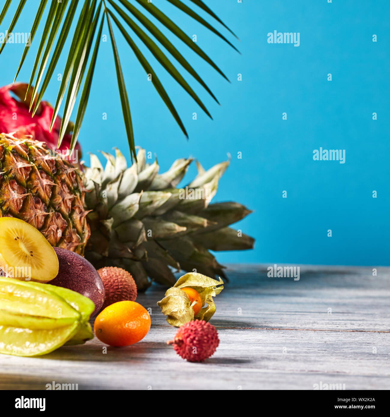 Varie succosa frutta esotica - litchi, ananas, carambole, litchi, dragon frutta sul grigio di un tavolo di legno su un blu. Alimentare l esotico Foto Stock