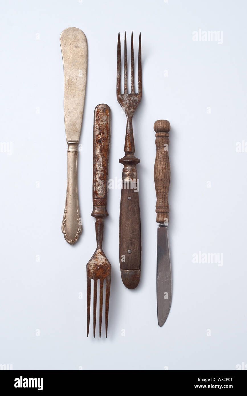 Collezione di vecchi in metallo con manico in legno le forcelle e i coltelli su uno sfondo grigio con copia spazio. Set vintage. Lay piatto Foto Stock