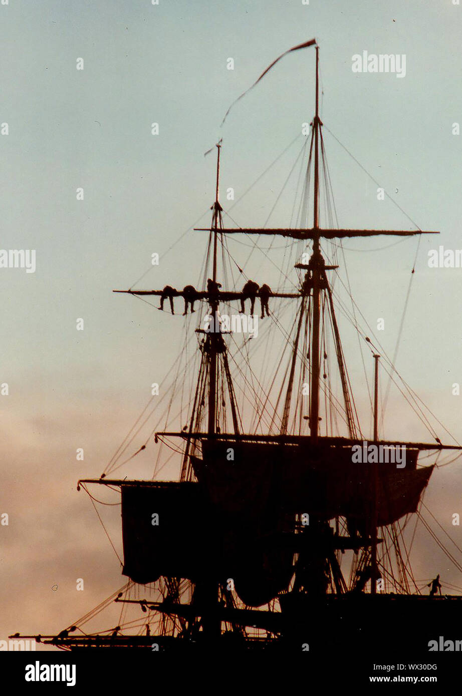 Una silhouette fotografia di marinai lavorando su un armamento di una moderna nave a vela (traino / abbassare le vele) al tramonto durante il tentativo di visitare l'Whitby, nello Yorkshire, Inghilterra in 2000. Foto Stock