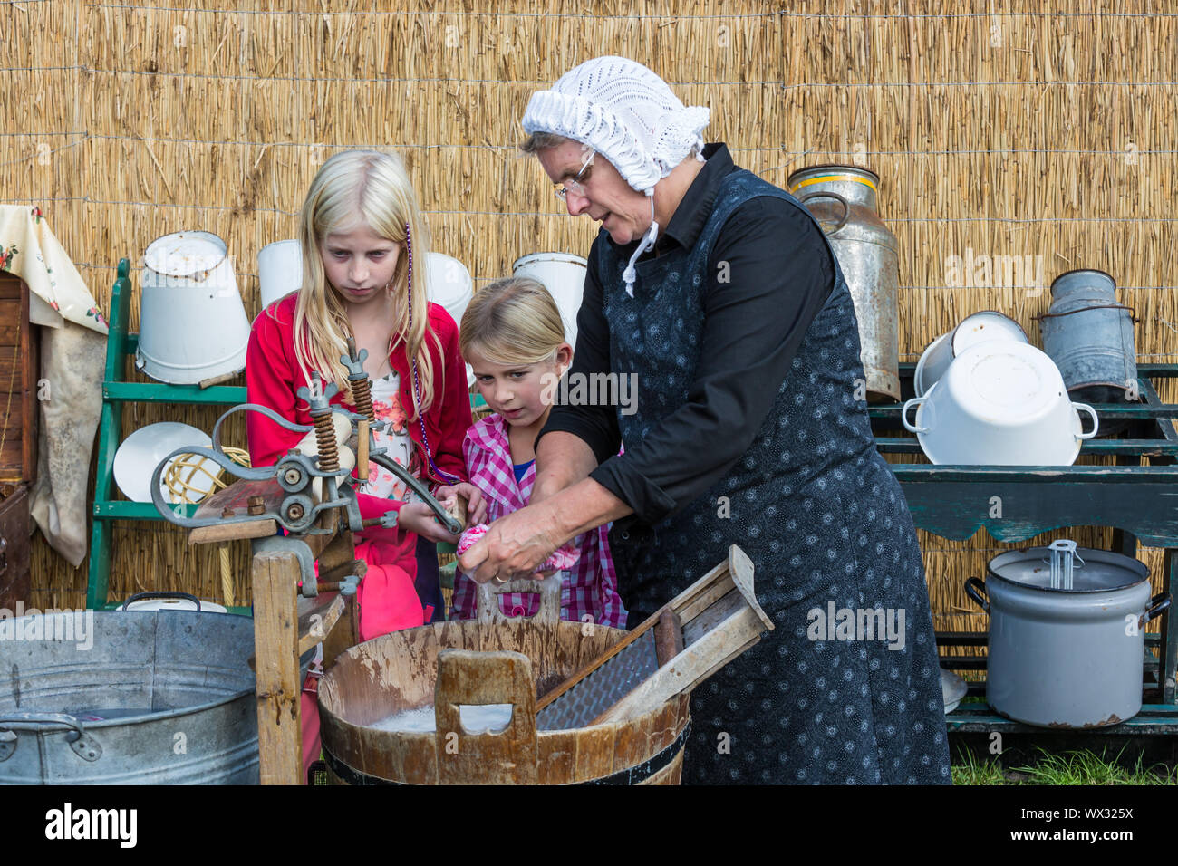 Agricoltore donna mostra l'uso di un tradizionale washhub durante un agricolo olandese festiva Foto Stock