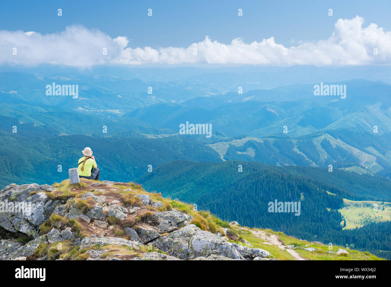Giovane donna seduta su montagne cliff Foto Stock