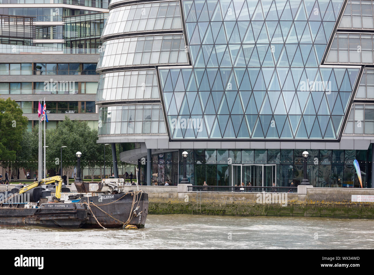 Moderni edifici lungo il fiume Tamigi con chiatte a Londra in Inghilterra Foto Stock