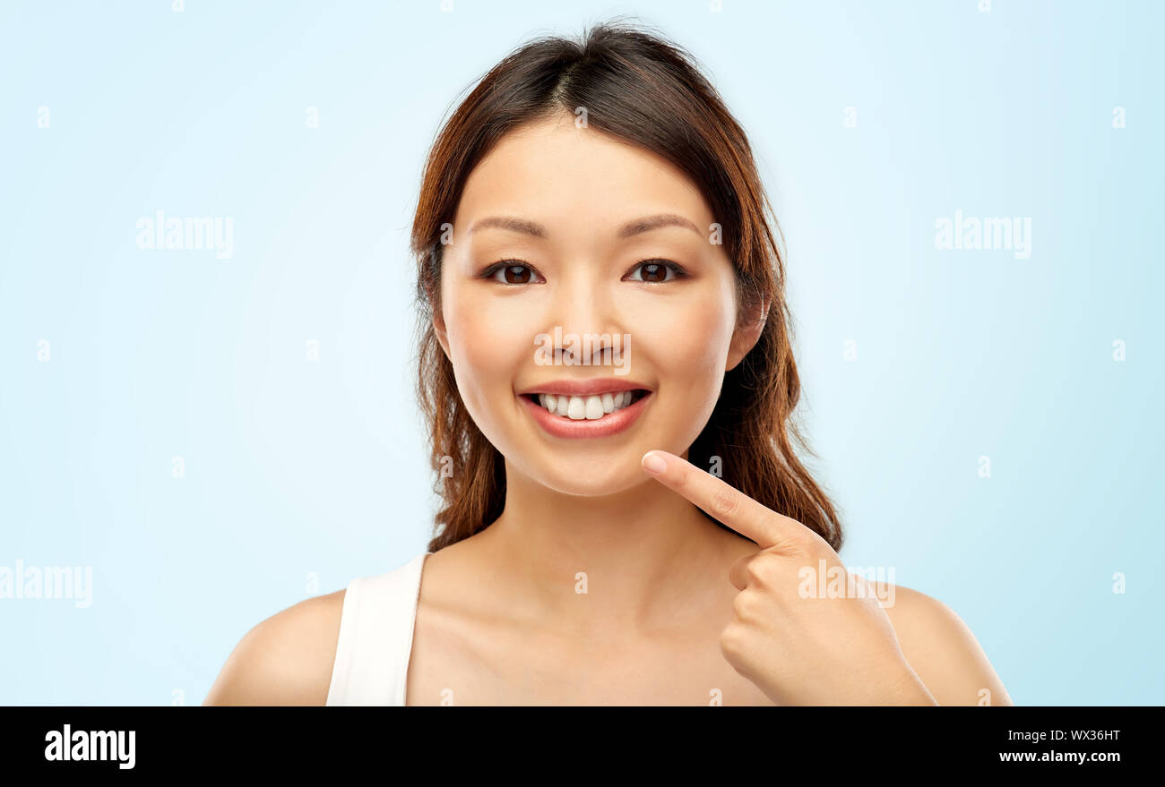 Sorridenti giovane donna asiatica di toccare il suo volto Foto Stock