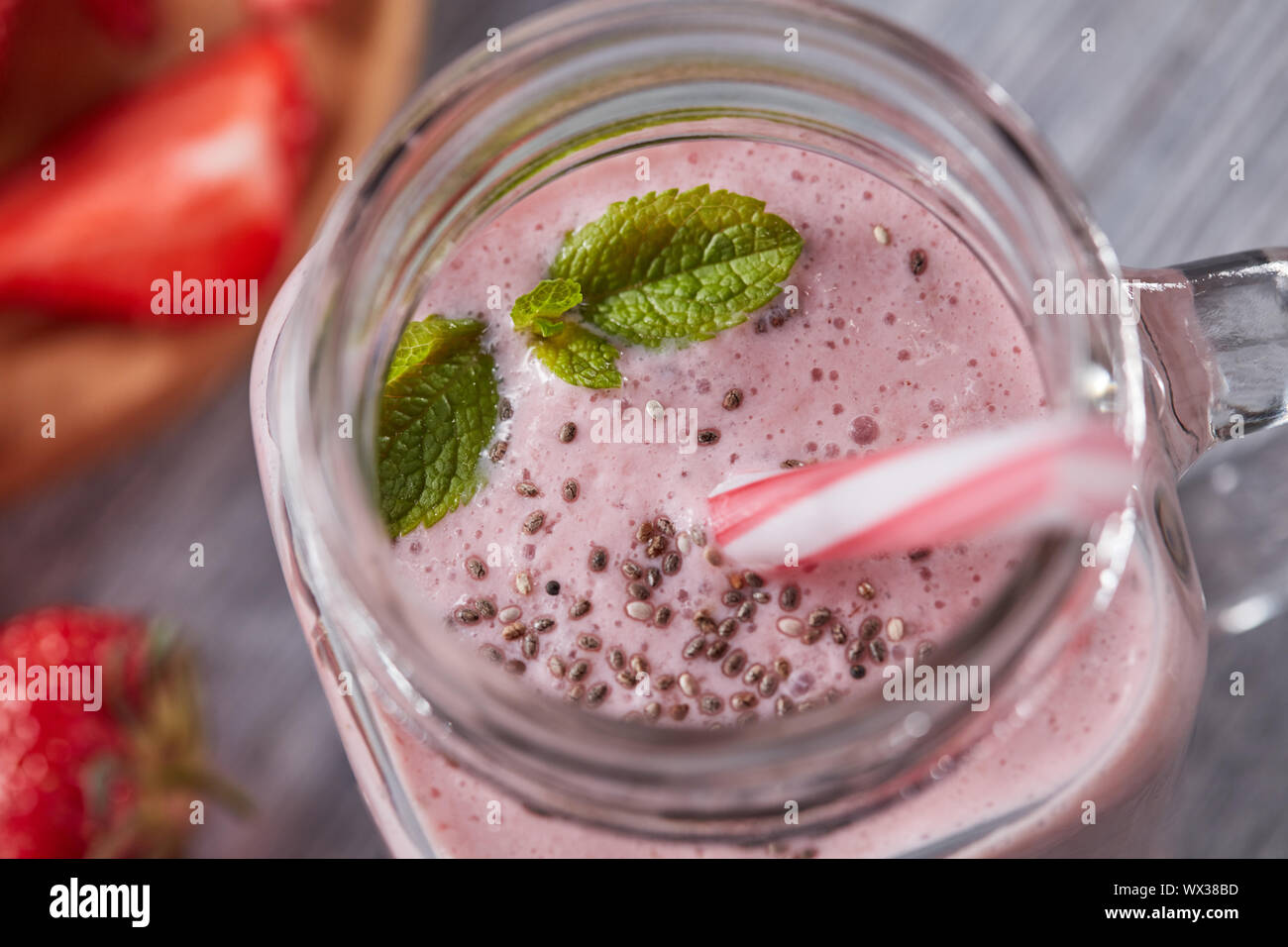 Primo piano di un preparato di fresco latteo-vitamina berry smoothie con chia semi e foglie di menta su un grigio Sfondo di legno. Vista superiore Foto Stock