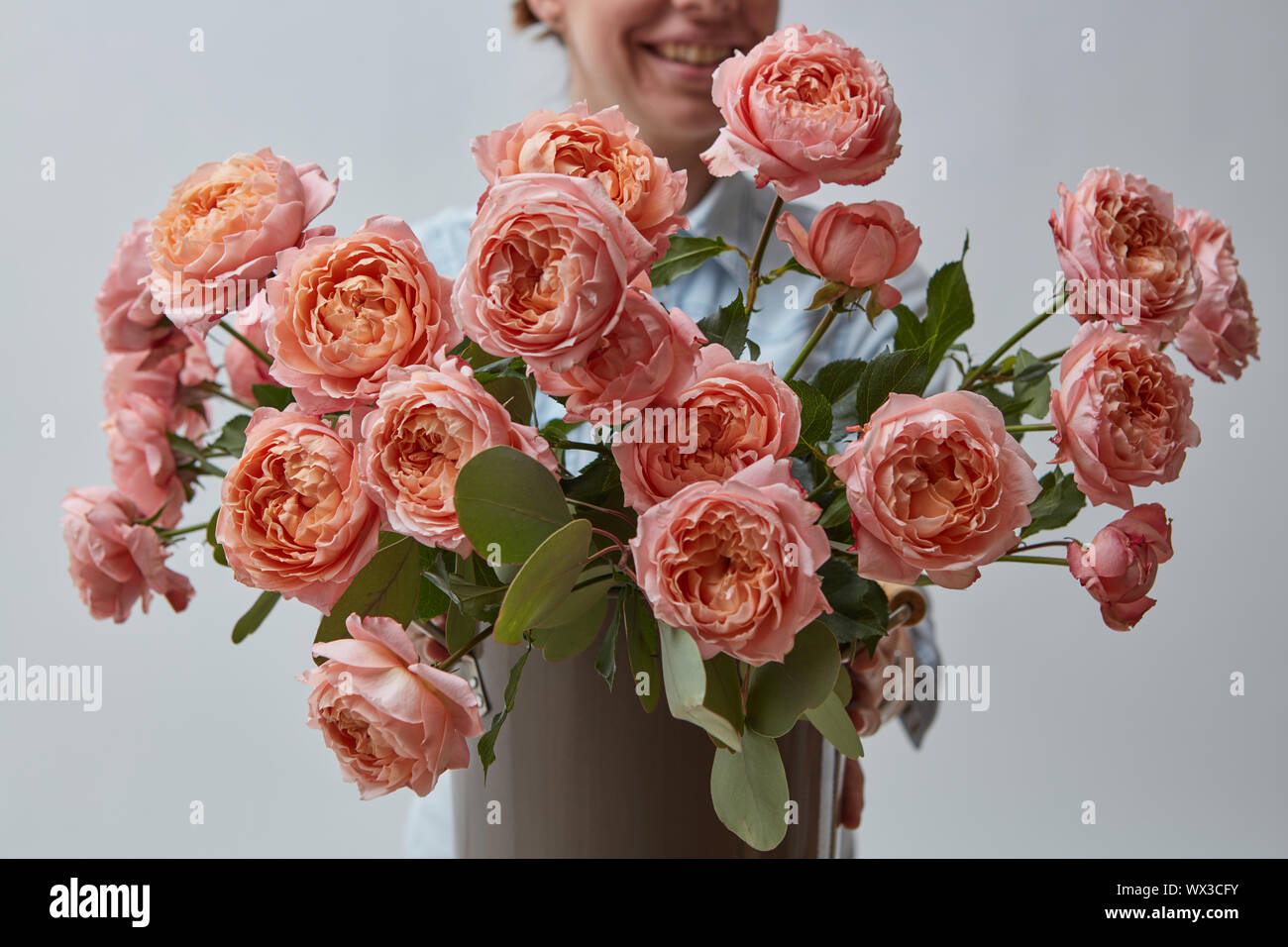 Belle le rose rosa, tenere una donna nelle mani su sfondo grigio. Festa della mamma Foto Stock