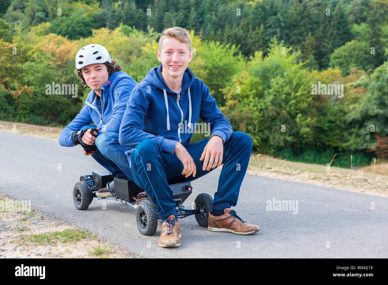 Due giovani uomini seduti sul mountainboard in natura Foto Stock