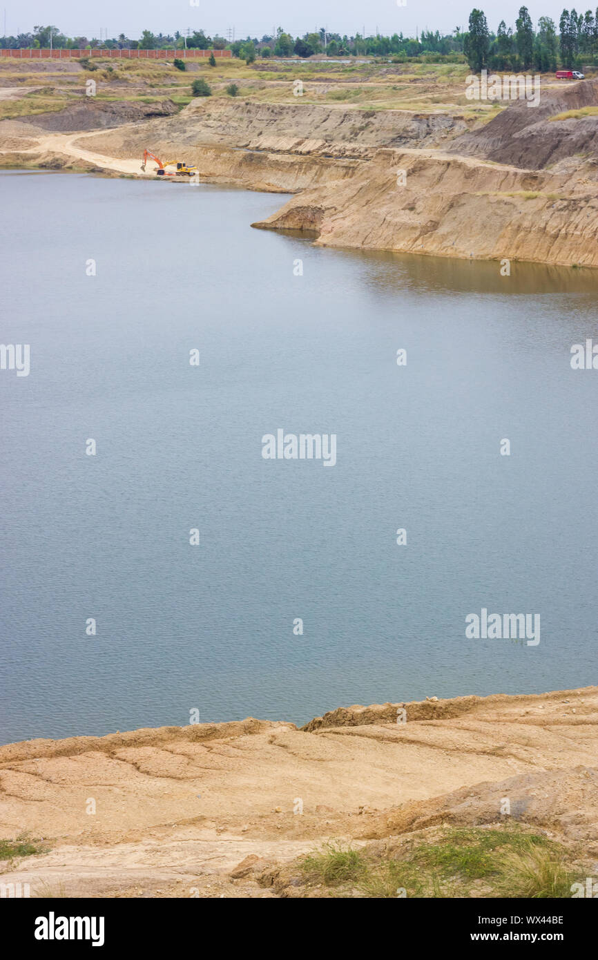Roccia del grande lago blu generata dal pozzo minerario della Thailandia con escavatore di lavoro in background Foto Stock