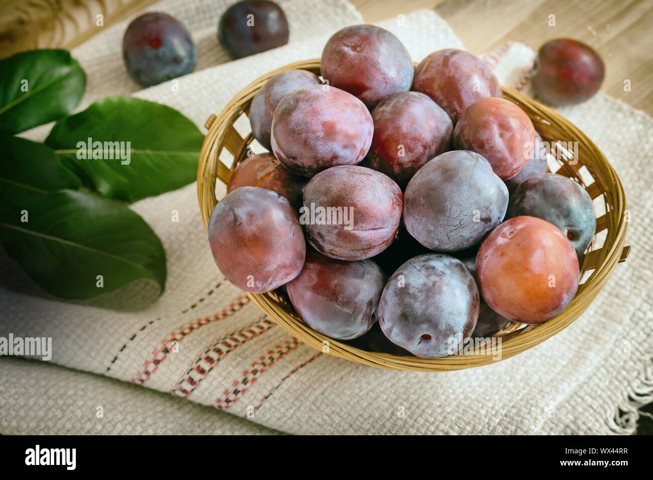 Grandi susine mature in un cesto di vimini. Foto Stock