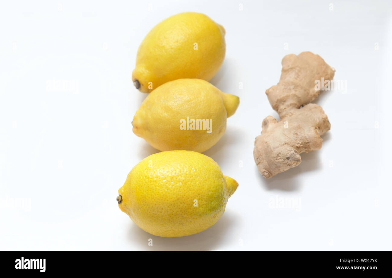 Tre gialli di limoni e di radice di zenzero su uno sfondo luminoso. Foto Stock