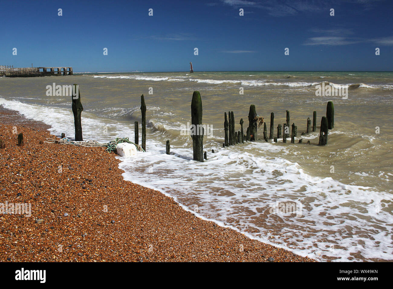 Il litorale a Rye Harbour in East Sussex con un frangiflutti decaduto in primo piano Foto Stock