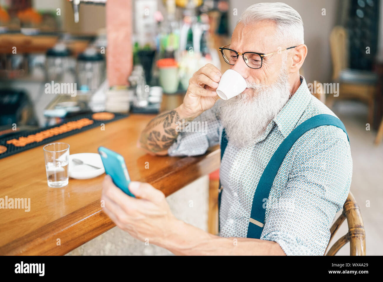 Senior uomo utilizzando mobile smartphone mentre si beve il caffè nel bar - Pensionati maschio di spendere tempo su reti sociali pur avendo una bevanda calda nel ristorante Foto Stock
