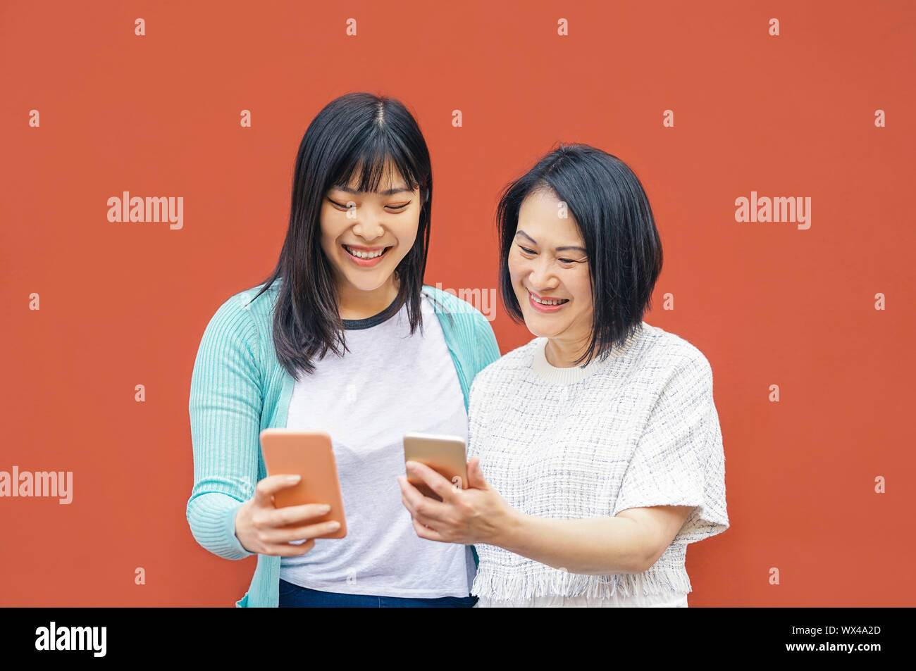 Asian madre e figlia utilizzando gli smartphone mobile outdoor - felice famiglia cinese per divertirti con le nuove tendenze della tecnologia app per i social media Foto Stock
