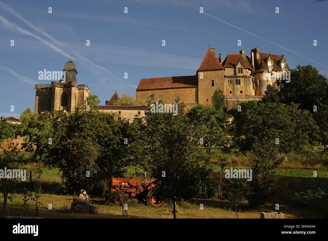 Chiesa francese e Chateau Hotel occupa un edificio di stile al di là del campo di Orchard con il trattore Foto Stock