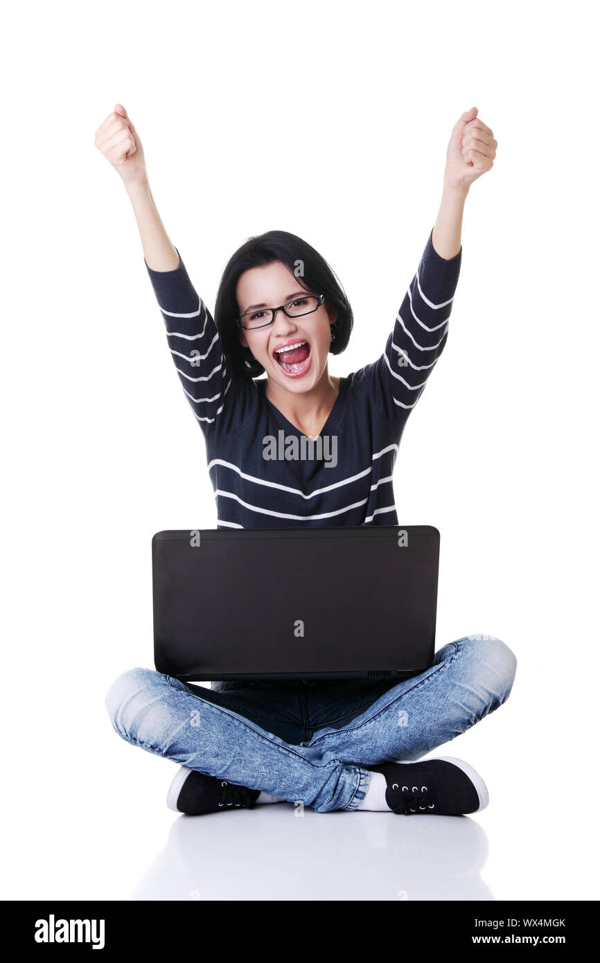 Felice giovane donna con i pugni fino utilizzando il suo laptop, isolato su bianco. Foto Stock