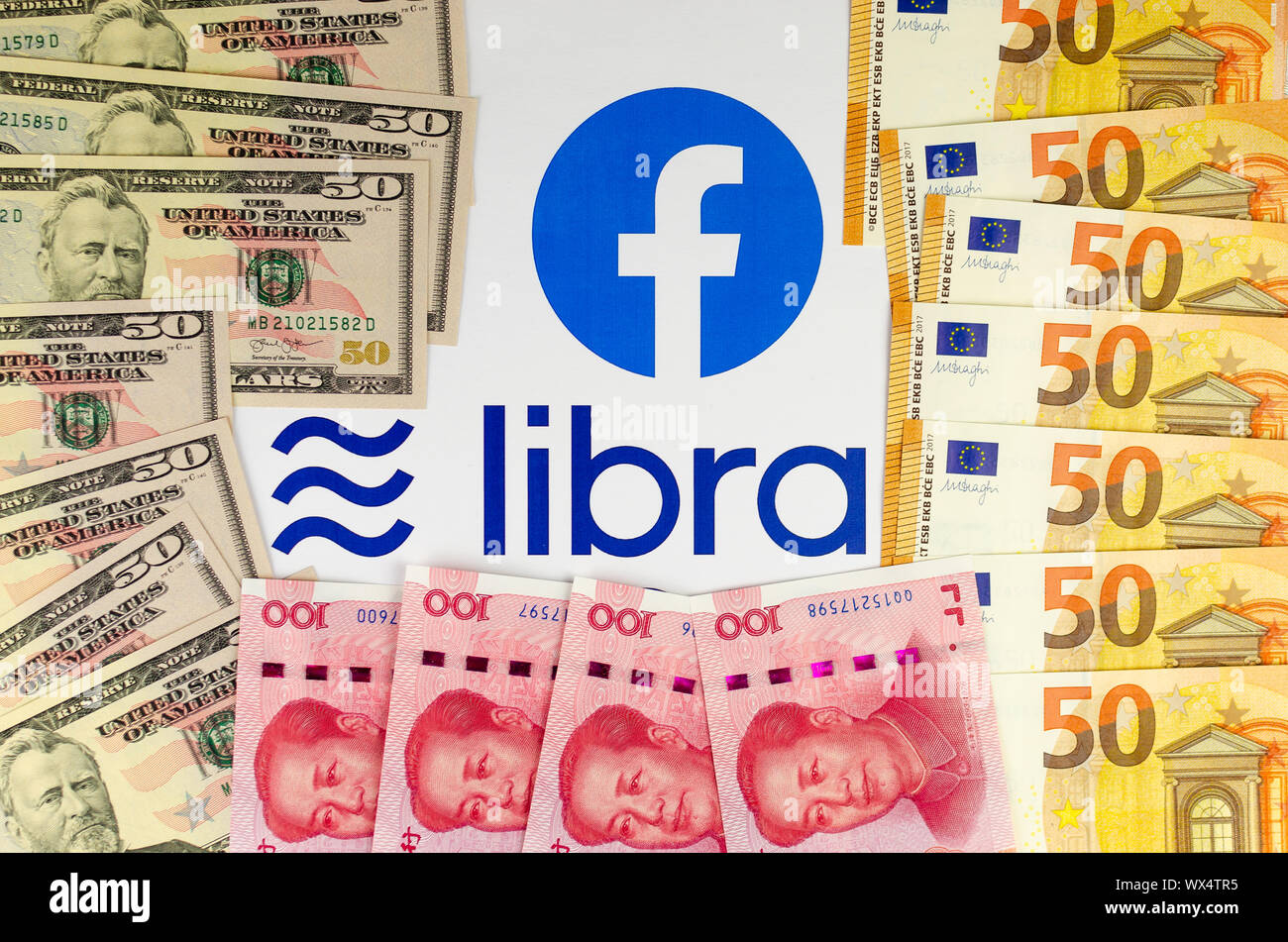 Facebook e la sua valuta Libra logo su brochure circondato da US dollari, euro e yuan cinese fatture. Foto Stock