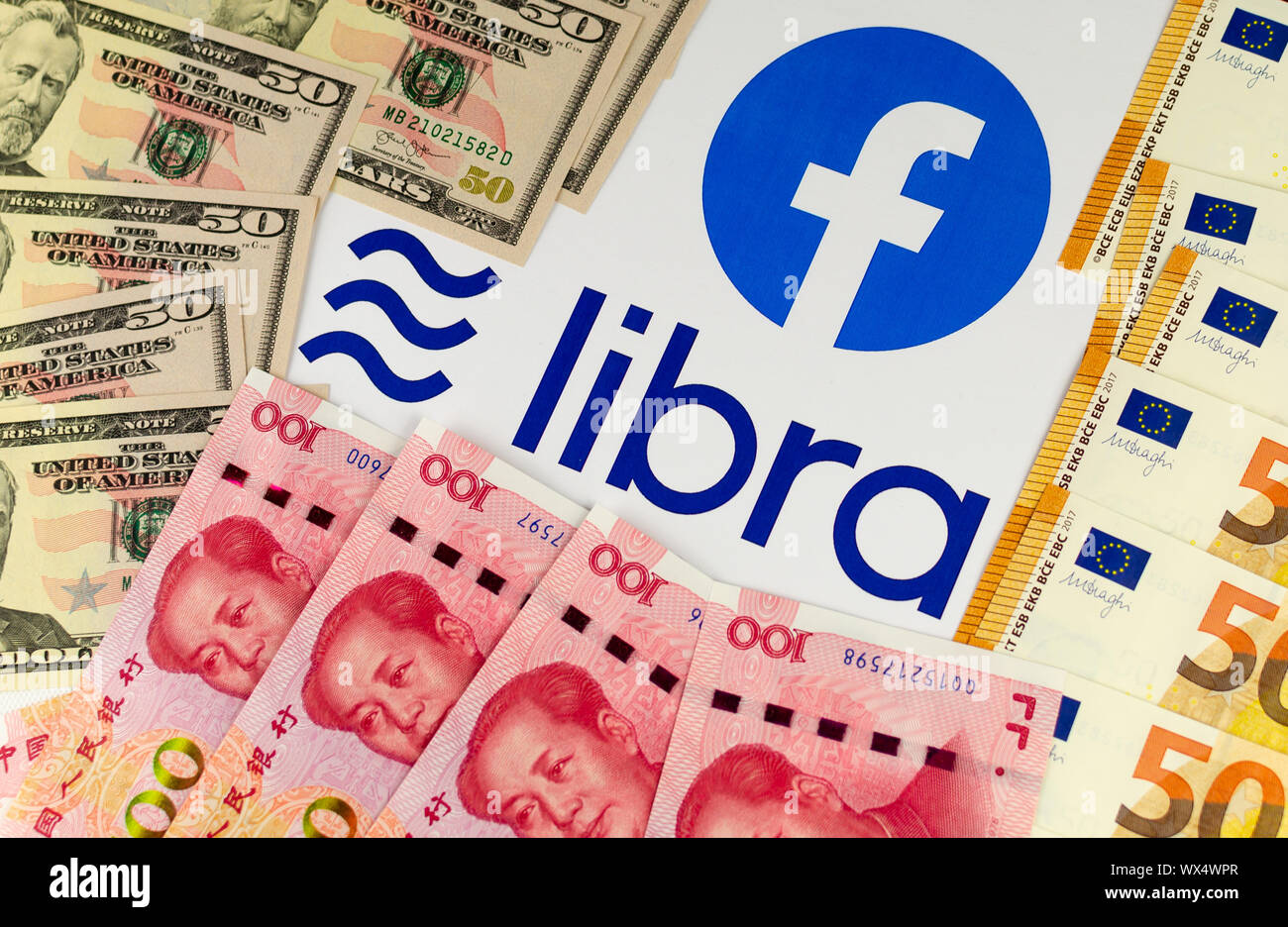 Facebook e la sua valuta Libra logo su brochure circondato da US dollari, euro e yuan cinese fatture. Foto Stock