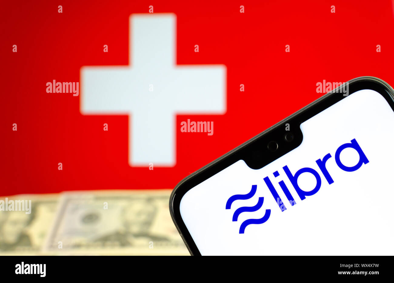 Facebook logo Libra sullo schermo dello smartphone con il dollaro note e la bandiera della Svizzera a sfondo sfocato. Concetto foto. Foto Stock