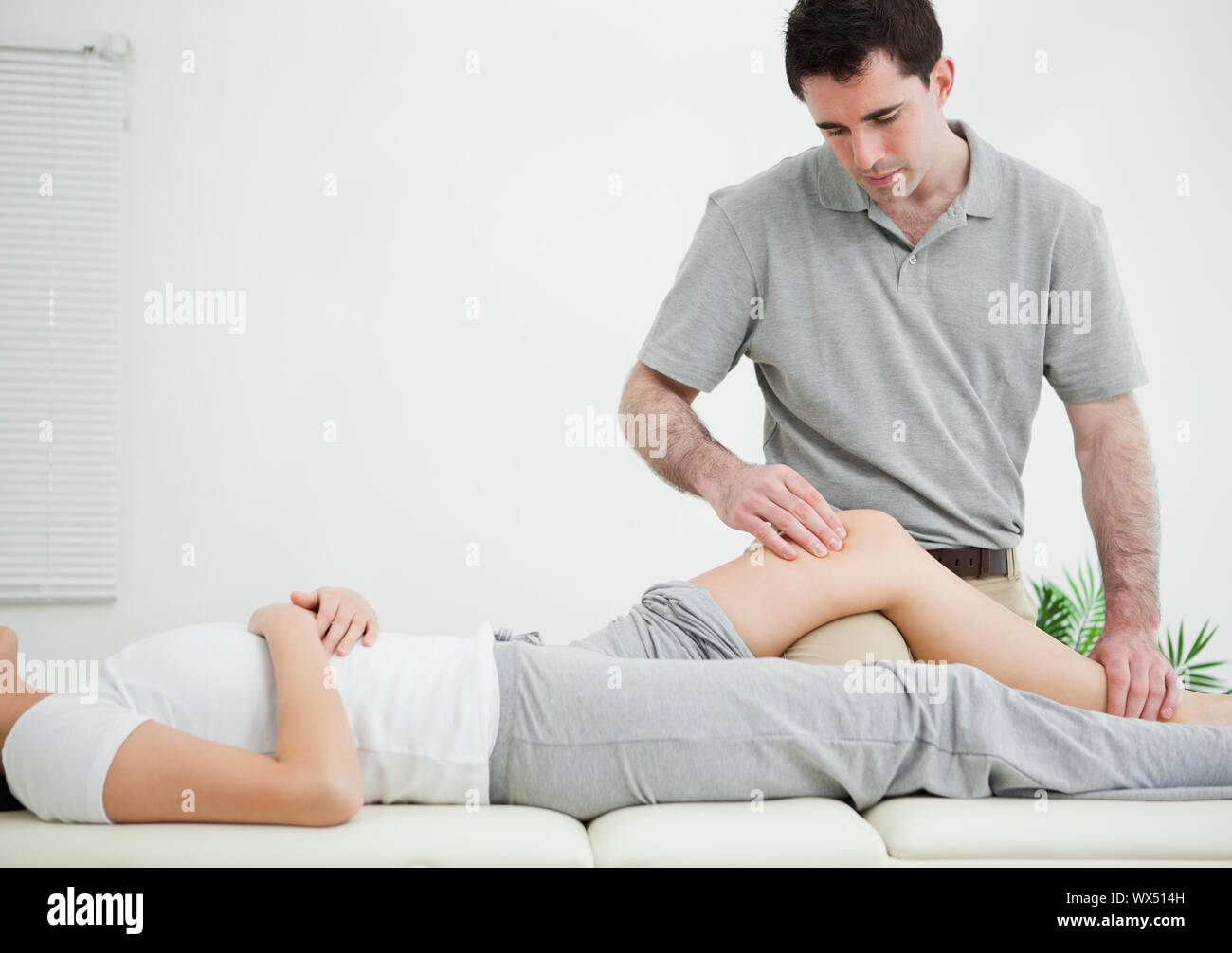 Donna sdraiata sulla schiena mentre viene massaggiato in una stanza Foto Stock