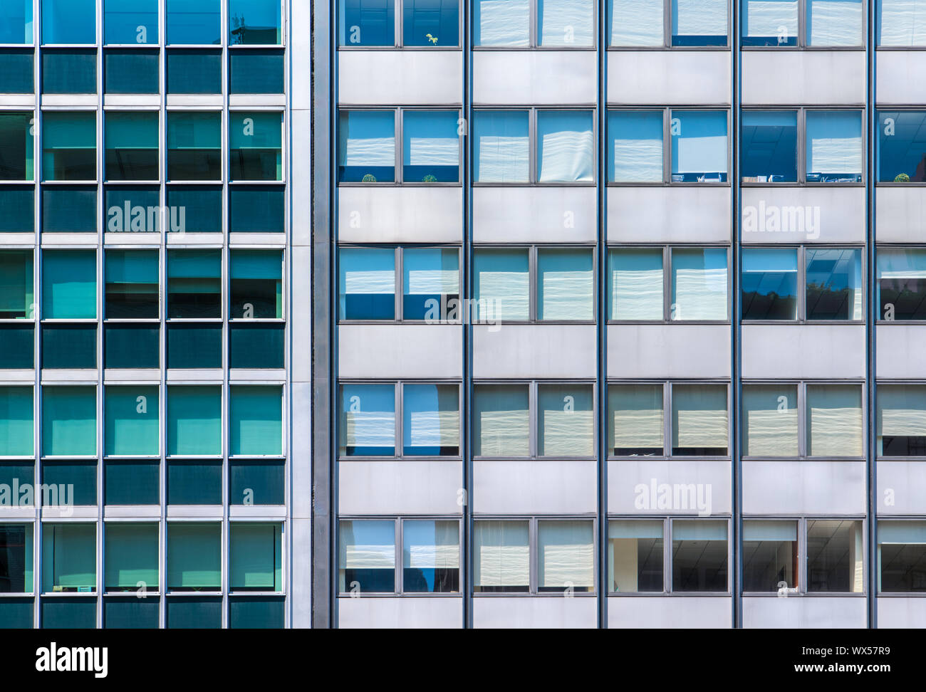 Una griglia di windows office in due moderni in vetro e acciaio fabbricati fianco a fianco con colori contrastanti Foto Stock