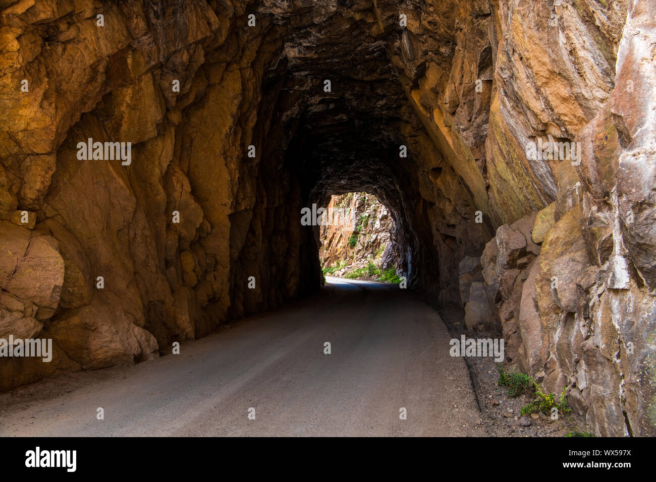 Tunnel e la curvatura della strada attraverso il Red Rock arenaria - Gilman gallerie nei pressi di Jemez Springs nel New Mexico settentrionale Foto Stock