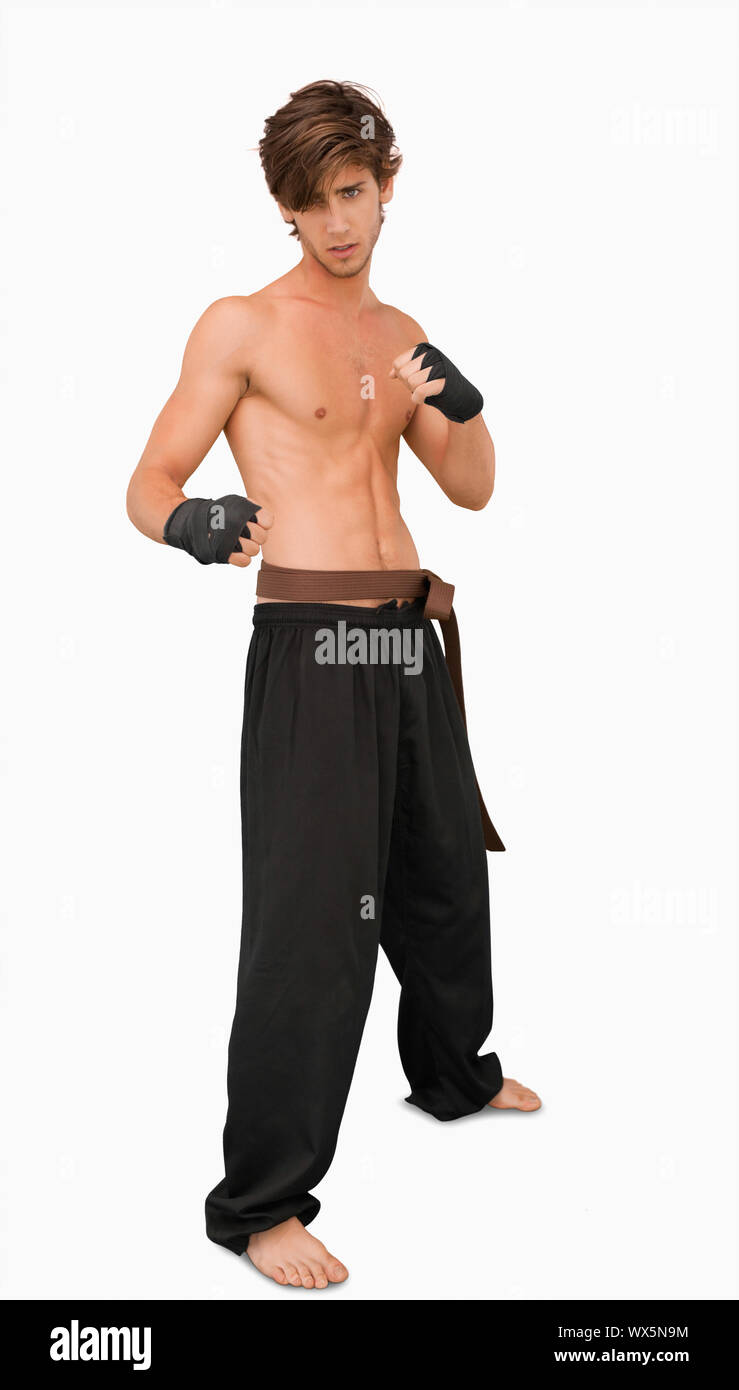 Arti marziali fighter in piedi in posa di combattimento contro uno sfondo bianco Foto Stock