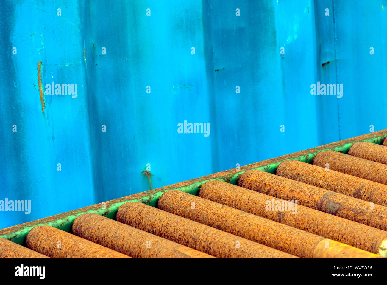 Un promemoria di un'altra azienda, con persiane blu un contenitore di spedizione al fianco di un acciaio arrugginito nastro trasportatore. Foto Stock