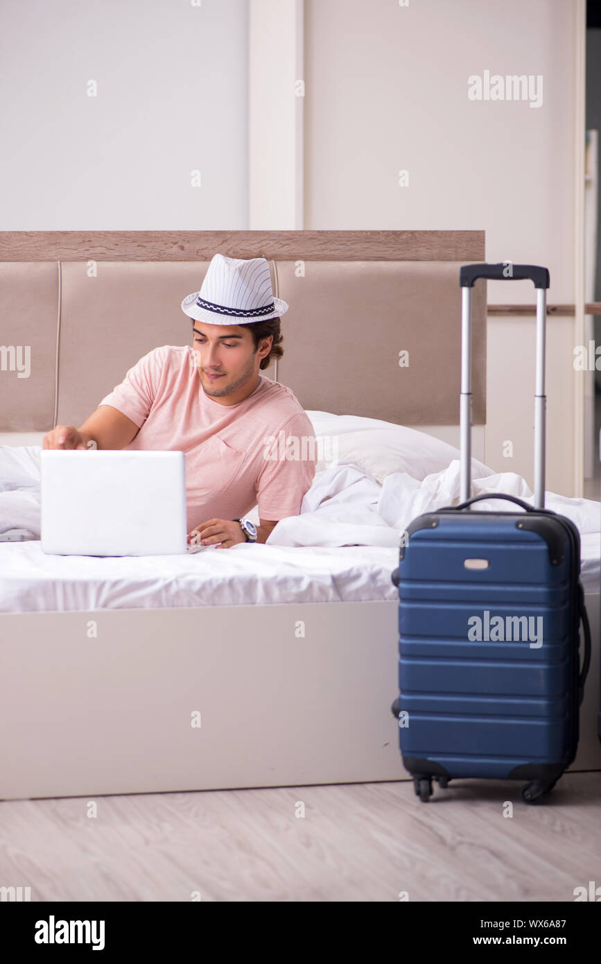 L'uomo con la valigia in camera da letto in attesa di viaggio Foto Stock