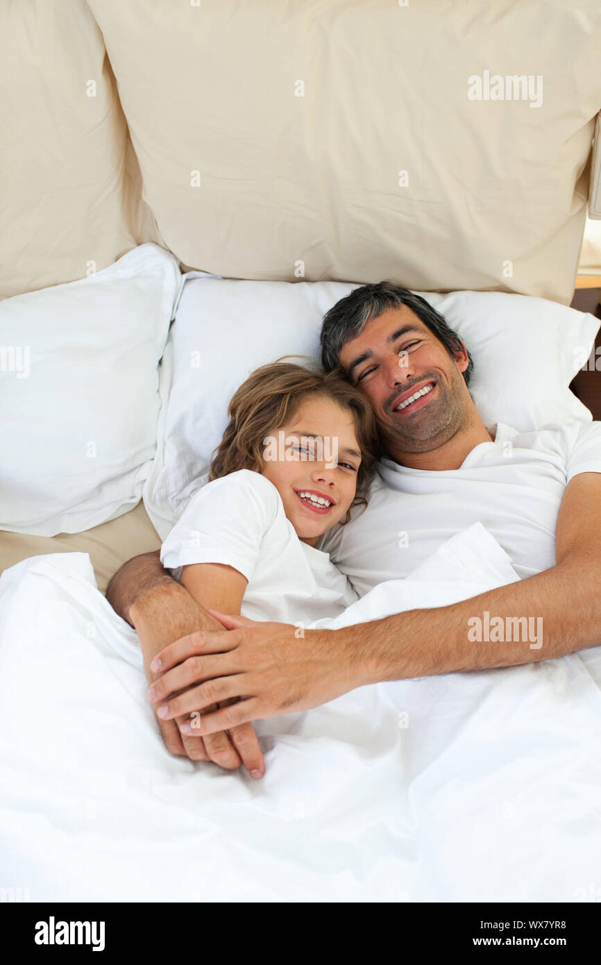 Attraente padre abbraccia il suo figlio che giace nel letto Foto Stock