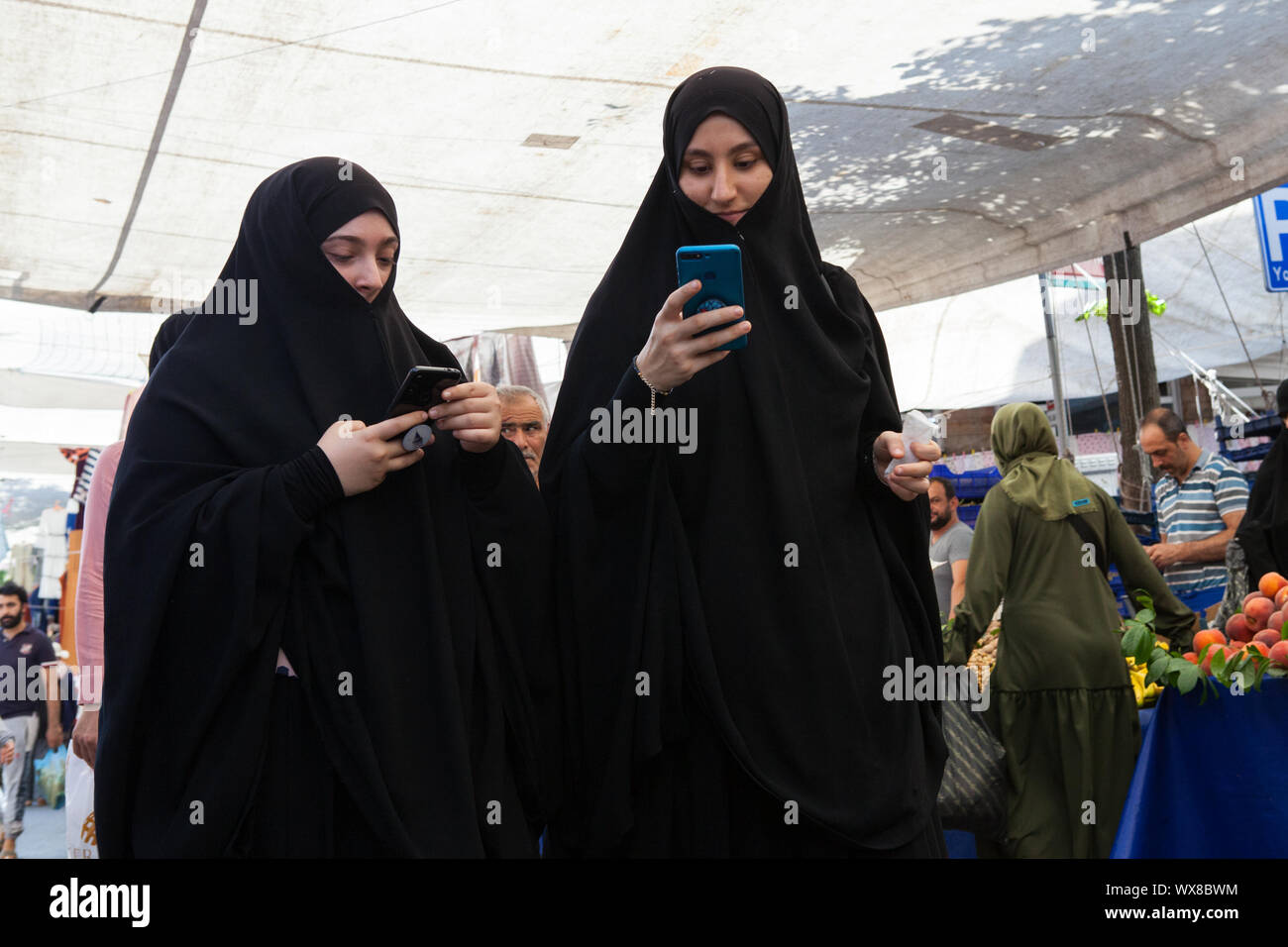 Le donne musulmane guardando i loro telefoni mobili nel quartiere Fatih di Istanbul Foto Stock