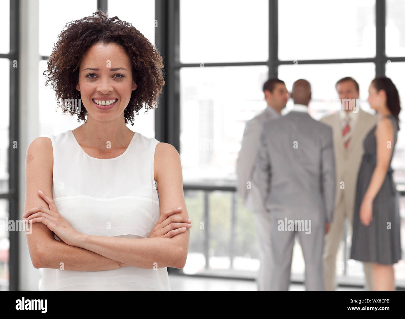 Imprenditrice sorridente sul telefono in ufficio con il suo team Foto Stock