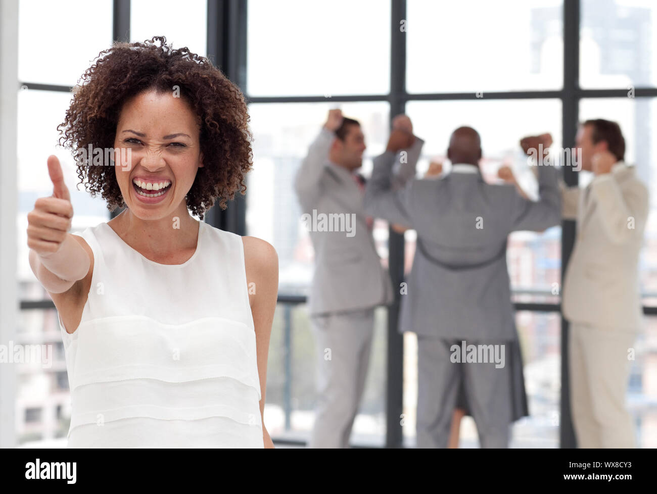 Attraente imprenditrice sul telefono in ufficio con il suo team Foto Stock